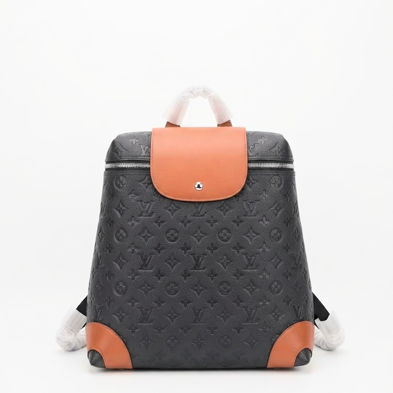 A LU monogram backpack in black coated canvas with tan leather accents on the front flap, bottom corners, and top handle, shown against a plain white background.