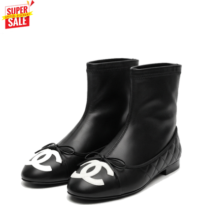 A pair of black leather ankle boots with white interlocking CC logos on the toes, bow details, and quilted soles, shown on a white background with a red 'SUPER SALE' graphic in the top-left corner.
