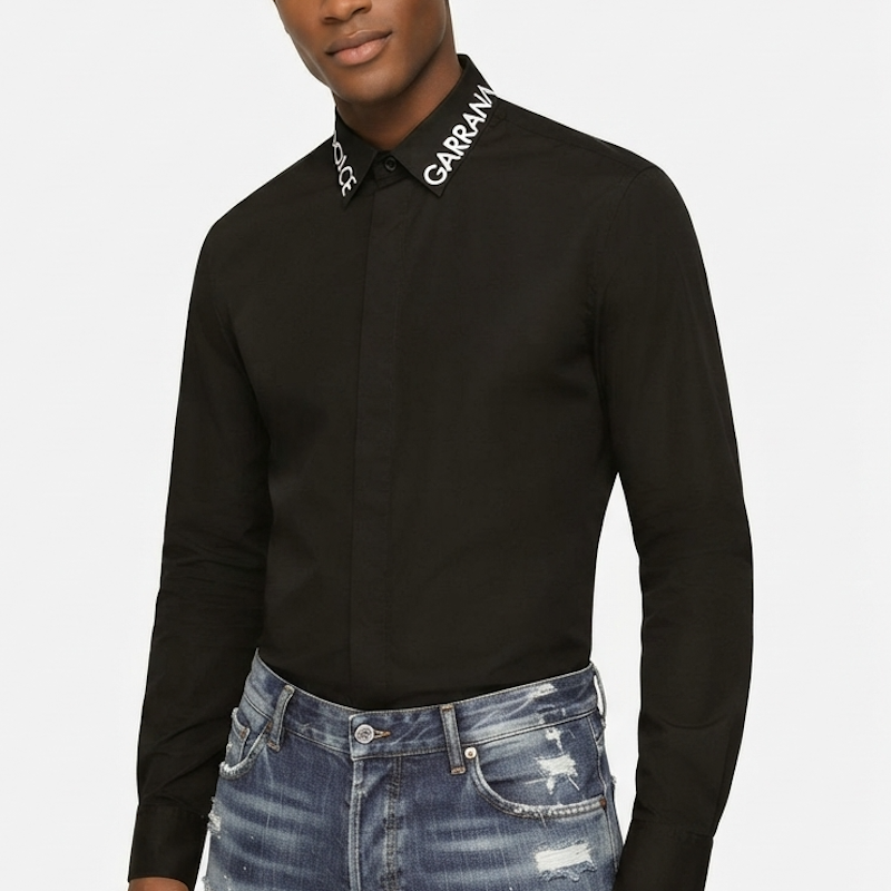 A man wearing a black long-sleeve button-down shirt with 'GARRAN' printed in white on the collar, paired with distressed blue jeans, against a light gray background.