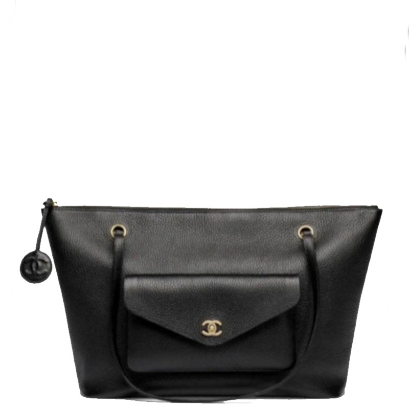 A black leather shoulder bag with a front flap pocket featuring a gold-tone interlocking CC logo, gold-tone grommets, and a black zipper pull with a round logo charm, shown on a plain white background.