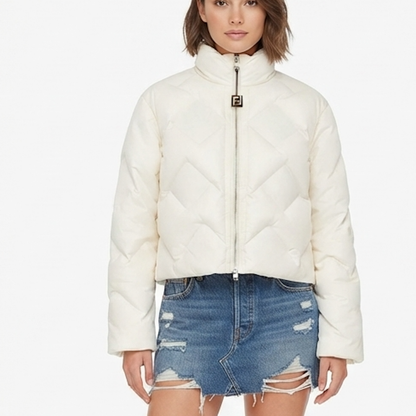 A model wearing a cream-colored, quilted puffer jacket with a high stand-up collar and a front zipper featuring an Fendi FF logo pull, paired with a distressed denim mini skirt against a plain white background.