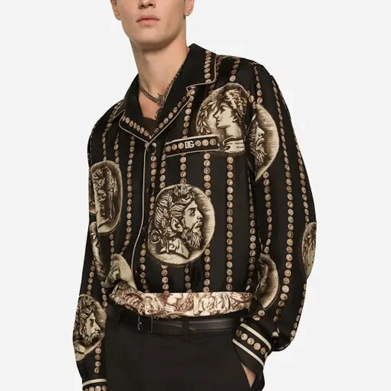 A man wearing a black Versace jacket with an ornate beige and gold Medusa-style print, paired with black trousers, against a light gray background.