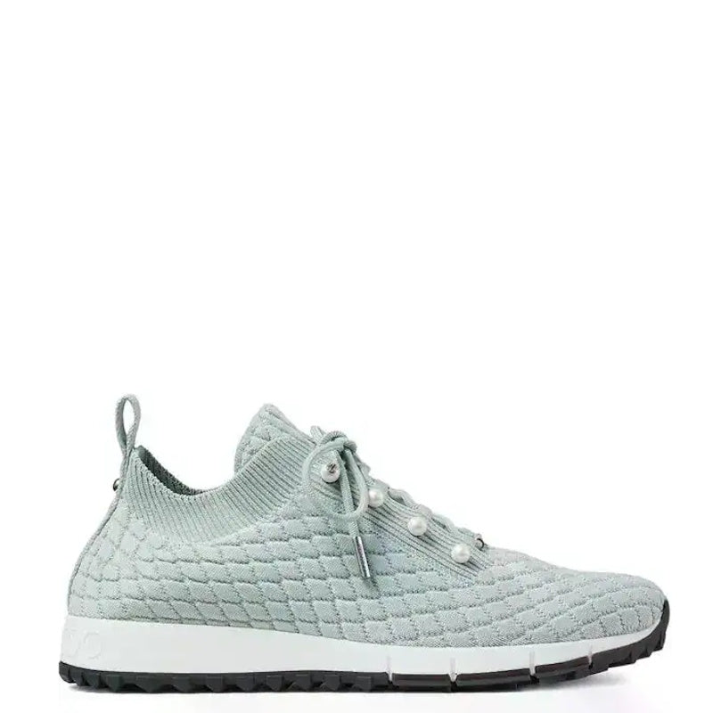 A light sage green knit slip-on sneaker with pearl-like eyelets and a white midsole, shown from a side profile on a white background.