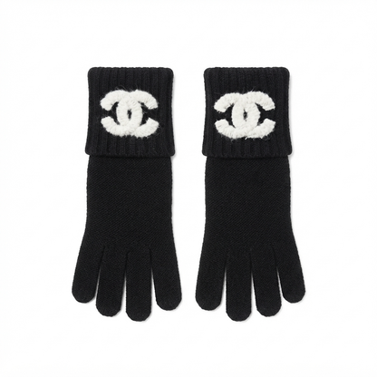 A pair of black knit gloves with white logo patches on the cuffs, displayed flat against a white background.