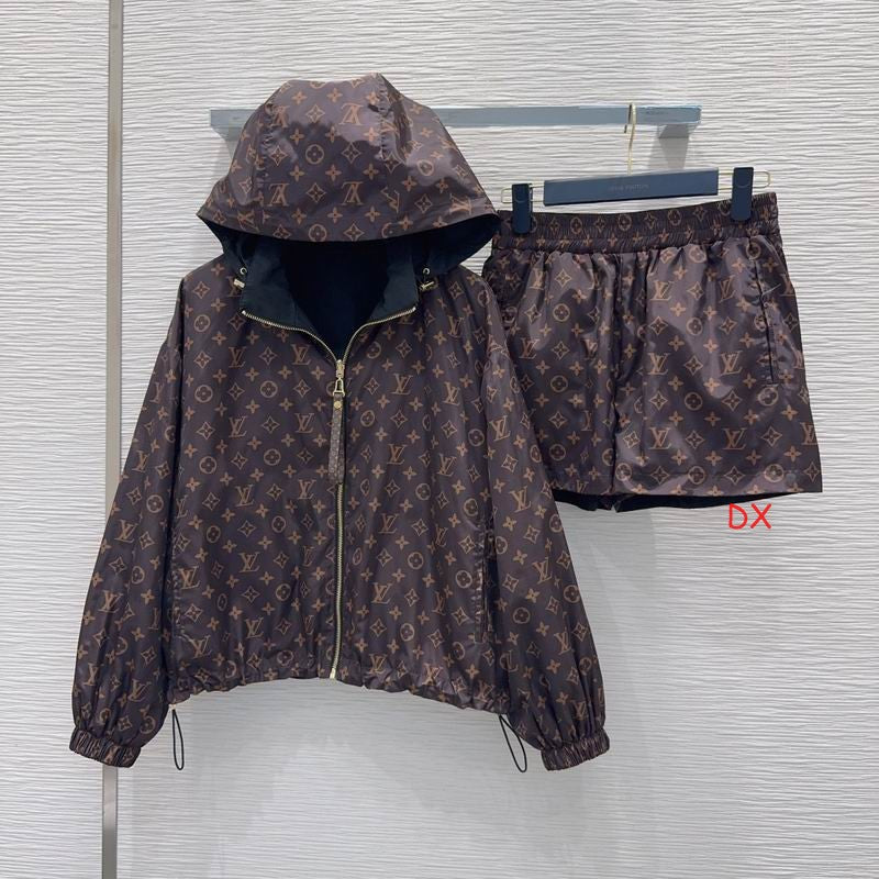 A brown Louis Vuitton monogram hooded jacket and matching shorts set hanging on a hanger bar against a light gray textured wall. The monogram pattern consists of brown and beige tones, with gold-toned zipper details.