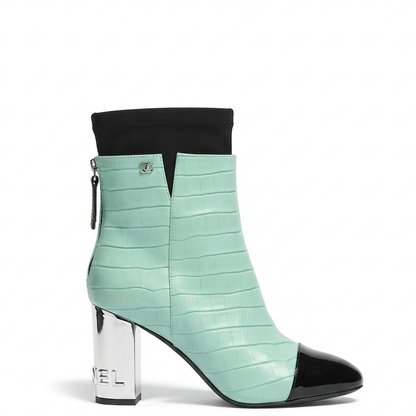 A mint green crocodile-embossed ankle boot with a black pointed toe, black elastic cuff, and a shiny silver block heel.