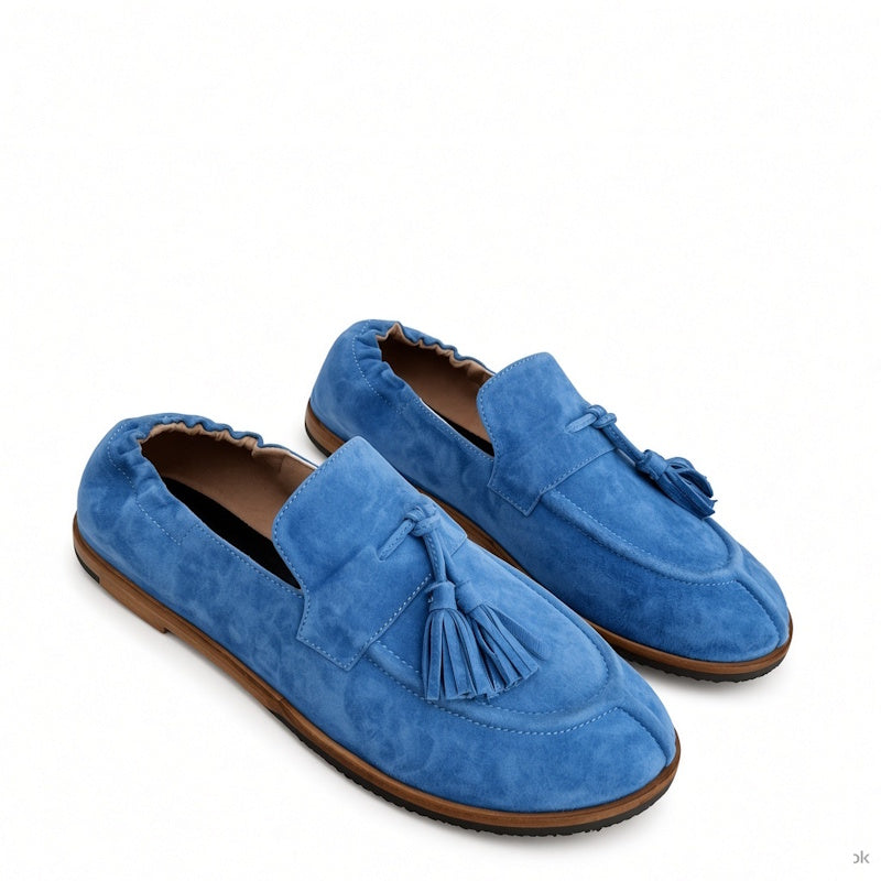 A pair of blue suede tassel loafers with brown soles, displayed on a clean white background.