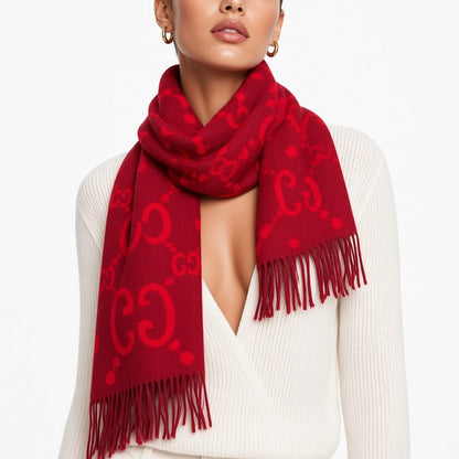 A red knit scarf with a tonal embossed GG monogram pattern and fringed ends, worn by a model in a white knit sweater against a plain white background.