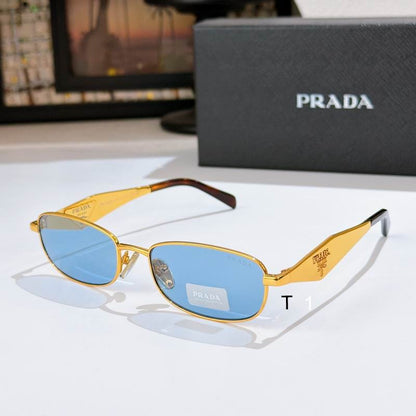 Prada gold metal sunglasses with light blue tinted lenses, displayed on a white surface with the Prada box in the background.