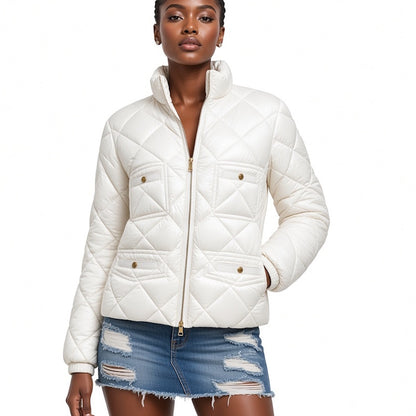 A model wearing a white quilted puffer jacket with a stand-up collar and gold-tone snap details, paired with a distressed denim mini skirt, against a plain white background.