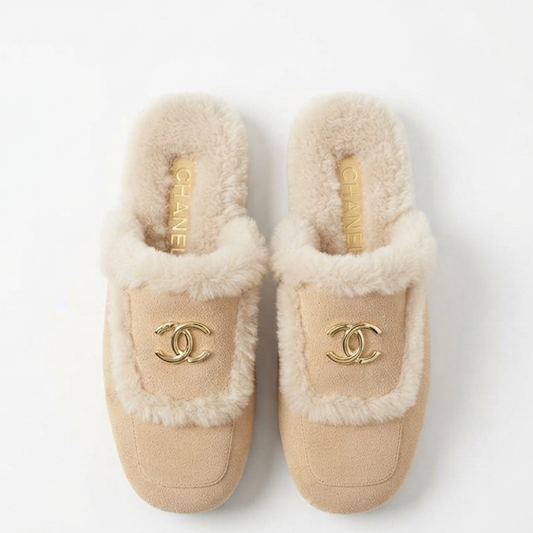 A pair of beige suede slippers with fluffy cream faux fur trim and gold-tone interlocking CC logos, shown from a top-down view on a white background.