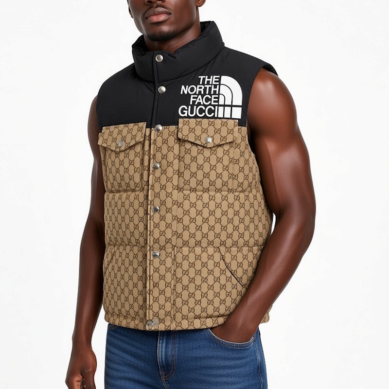 A man wearing a sleeveless quilted puffer vest with a black upper yoke and a tan-and-black monogram patterned lower body. The vest features a white 'THE NORTH FACE ' logo on the chest.