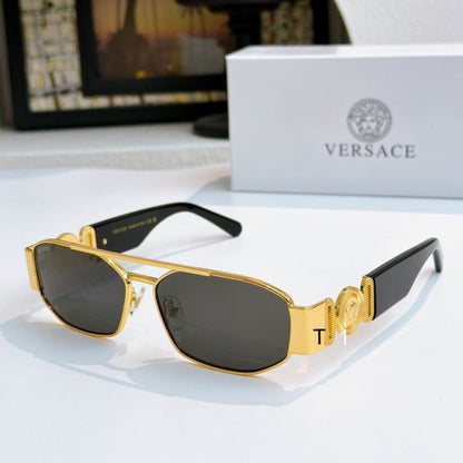 Gold-framed Versace sunglasses with dark lenses and black temples, displayed on a white surface with a white Versace box in the background.