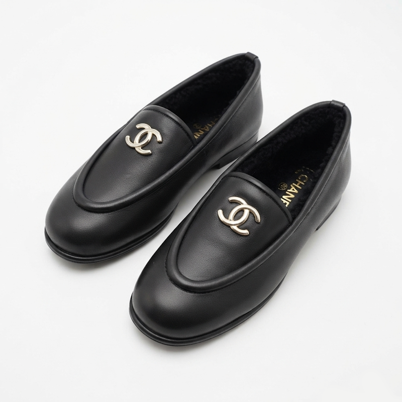 A pair of black leather  loafers with gold-tone interlocking CC logos on the toe, displayed on a clean white background.