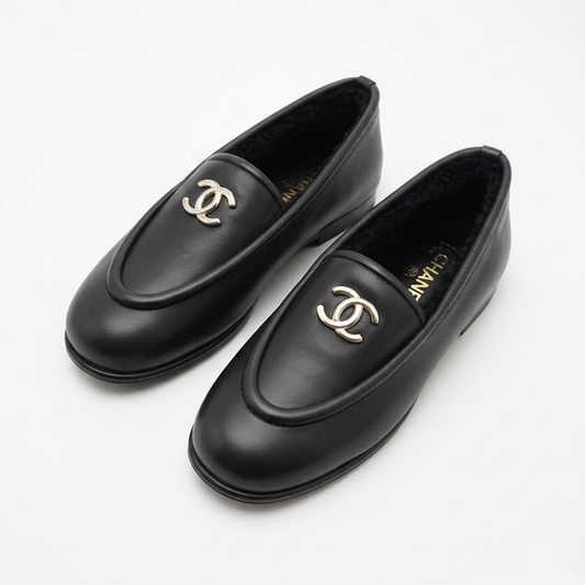 A pair of black leather  loafers with gold-tone interlocking CC logos on the toe, displayed on a clean white background.