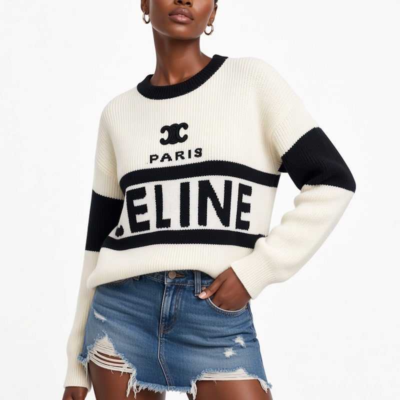 A model wearing a cream and black Paris knit sweater with distressed denim shorts, shown from the nose down against a plain white background.