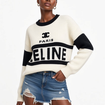 A model wearing a cream and black Paris knit sweater with distressed denim shorts, shown from the nose down against a plain white background.