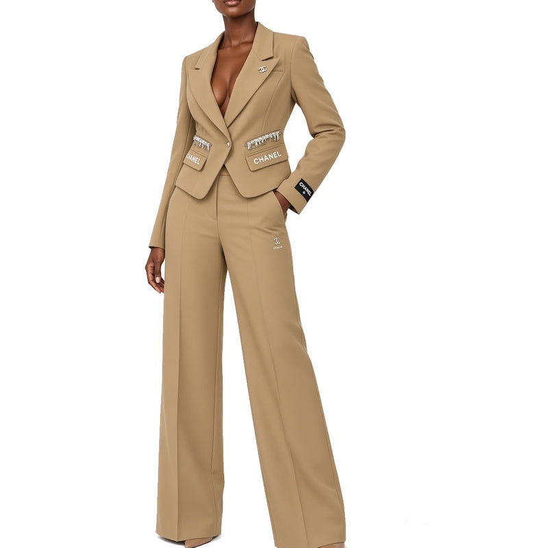 A model wearing a beige Chanel suit set consisting of a double-breasted blazer with  and 'PROPERTY' patch pockets, and matching wide-leg trousers, against a plain white background.