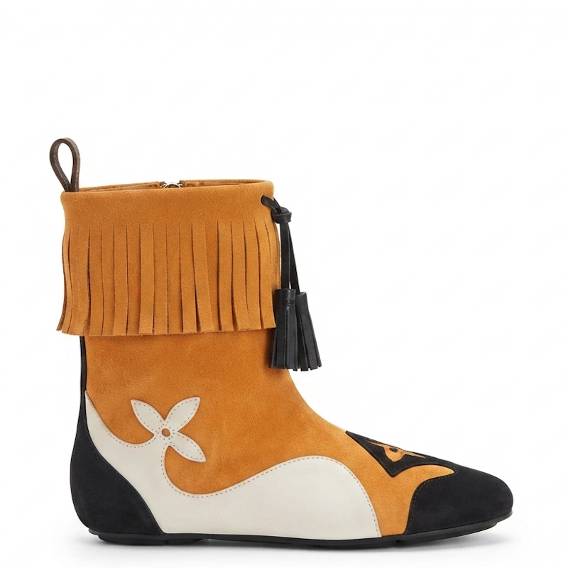 A women's ankle boot featuring a color-blocked design in mustard yellow, black, and off-white. The upper portion is mustard yellow suede with a wide fringe trim and a black tassel, while the lower section features black and off-white panels with a stylized white flower motif.