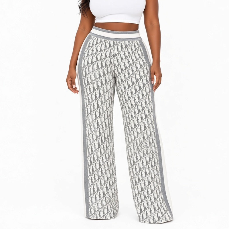 A model wearing high-waisted wide-leg pants featuring an all-over gray and white monogram pattern with solid gray side panels and a white waistband, shown against a plain white background.
