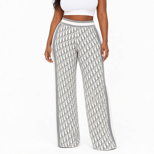 A model wearing high-waisted wide-leg pants featuring an all-over gray and white monogram pattern with solid gray side panels and a white waistband, shown against a plain white background.