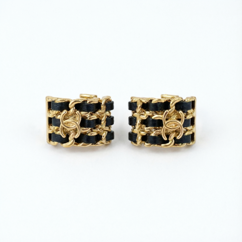 A pair of gold-tone chain-link cuff earrings with black woven ribbon detailing, displayed on a clean white background.