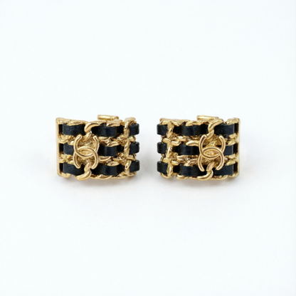 A pair of gold-tone chain-link cuff earrings with black woven ribbon detailing, displayed on a clean white background.