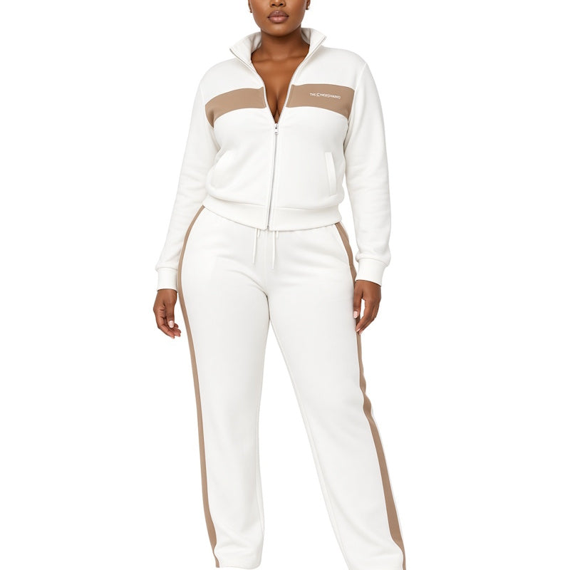 A woman modeling a white zip-up track jacket and matching sweatpants set with beige color-block panels on the chest and along the outer legs, shown against a plain white background.