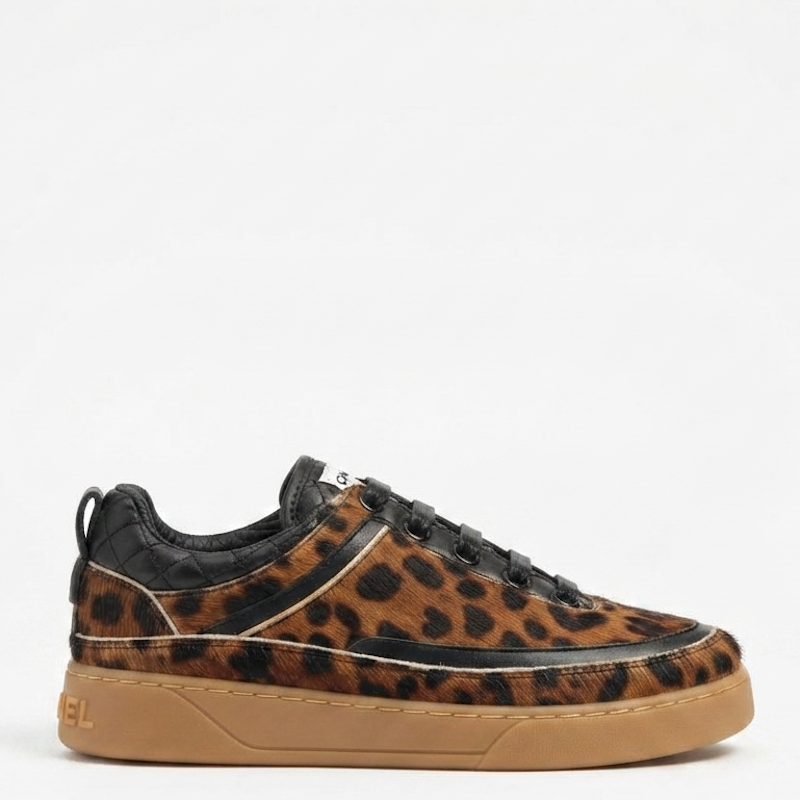 A low-top sneaker featuring a brown and black leopard print upper, black leather trim, black laces, and a gum brown sole, shown against a plain white background.