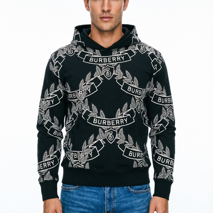 A man wearing a black Buber hoodie with a white allover logo print, paired with blue jeans, against a plain white background.