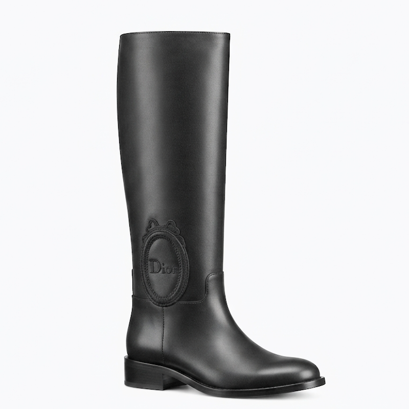 A single black leather knee-high boot with a low block heel and a debossed ogo medallion on the side, shown against a plain white background.