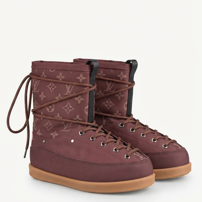A pair of  mid-calf boots in a burgundy monogram canvas with brown laces and gum soles, shown against a plain off-white background.
