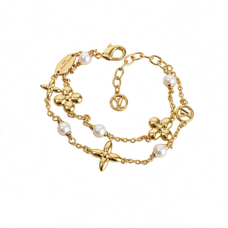 A gold-tone chain bracelet featuring four-flower motifs, white faux pearls, and circular interlocking LV logos, displayed on a clean white background.