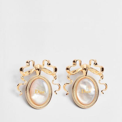 A pair of gold-tone  earrings with oval mother-of-pearl cabochons and decorative ribbon-like tops, shown on a light gray background.