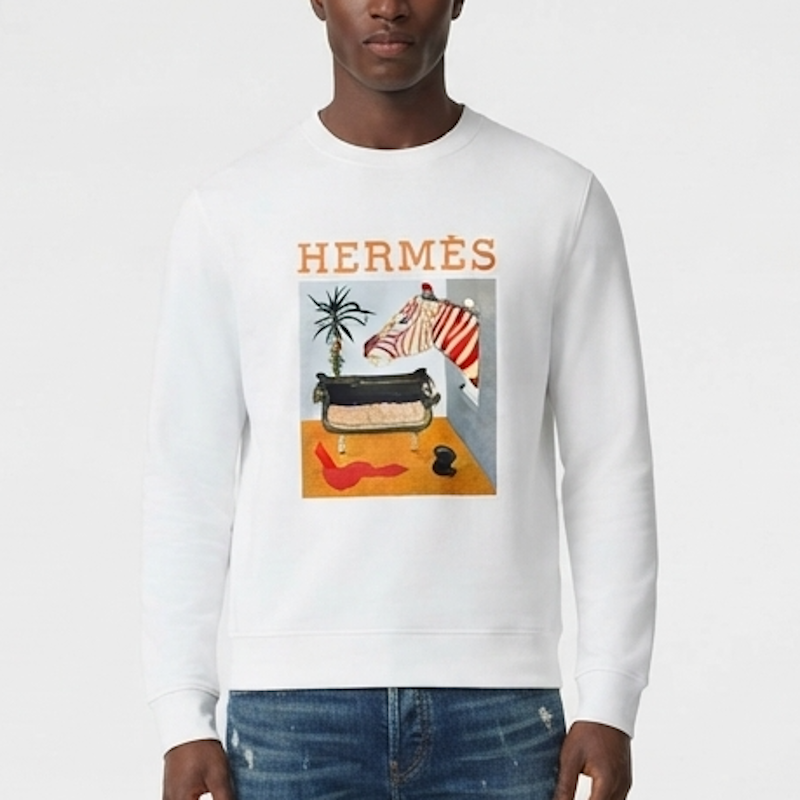 A man wearing a white crewneck sweatshirt featuring a colorful graphic print of a suitcase, palm tree, and a zebra with the word  printed above it, paired with blue jeans against a light gray background.
