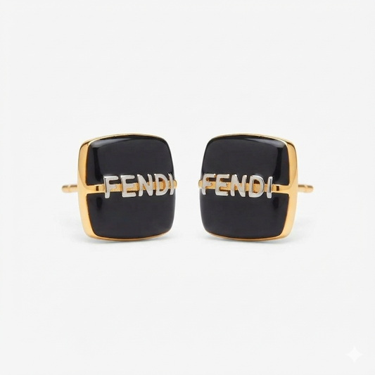 A pair of Fendi square cufflinks with black enamel faces, gold-tone metal borders, and the Fendi logo in silver-tone lettering across the center, set against a plain light gray background.