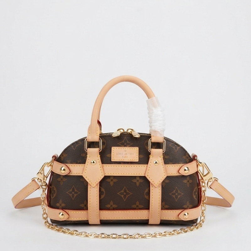  monogram canvas dome handbag with tan leather trim, gold-tone hardware, top handle, and chain strap, photographed on a clean light gray background.