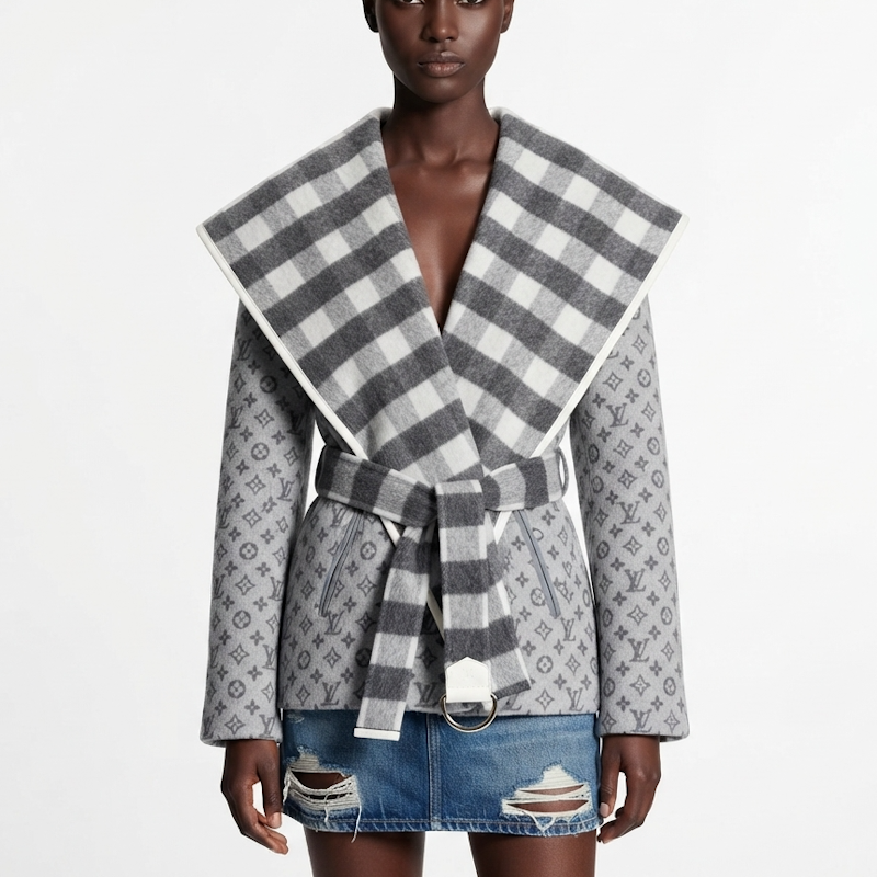 A model wearing a monogram patterned wrap coat with a large striped collar and tie belt, styled with a denim mini skirt against a plain white background.