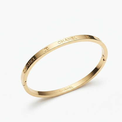 A gold-toned  bangle bracelet with engraved CHA lettering, shown on a clean white background.
