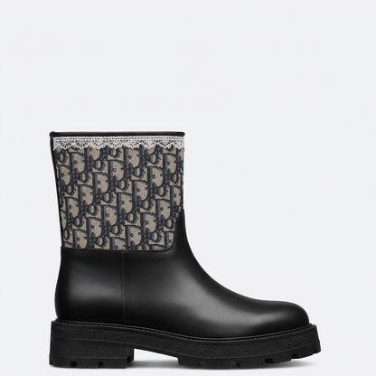 A black leather ankle boot with a thick lug sole, featuring a beige and black  Oblique monogram patterned fabric collar.