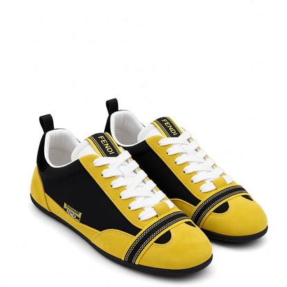 A pair of Fendi low-top sneakers in yellow and black suede, featuring white laces, a white tongue label with black Fendi branding, and a black toe cap with a yellow V-edge accent.