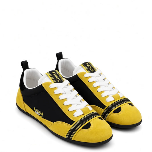 A pair of Fendi low-top sneakers in yellow and black suede, featuring white laces, a white tongue label with black Fendi branding, and a black toe cap with a yellow V-edge accent.