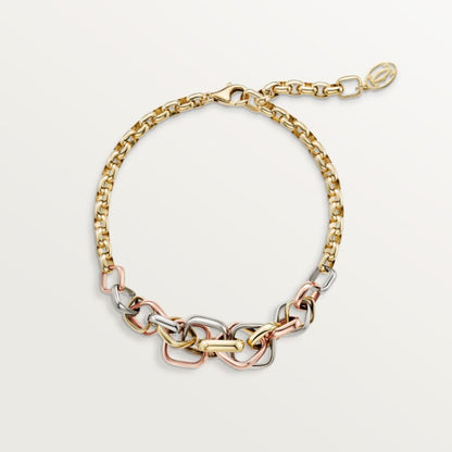 Gold, silver, and rose gold chain bracelet on a light gray background