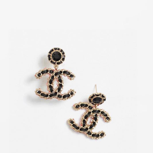 A pair of  logo stud earrings in gold-tone metal with black enamel detailing and a central black stone, displayed on a clean white background.